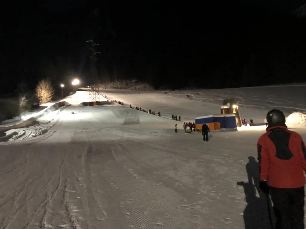 Beleuchtete Rodelbahn bei Nacht.